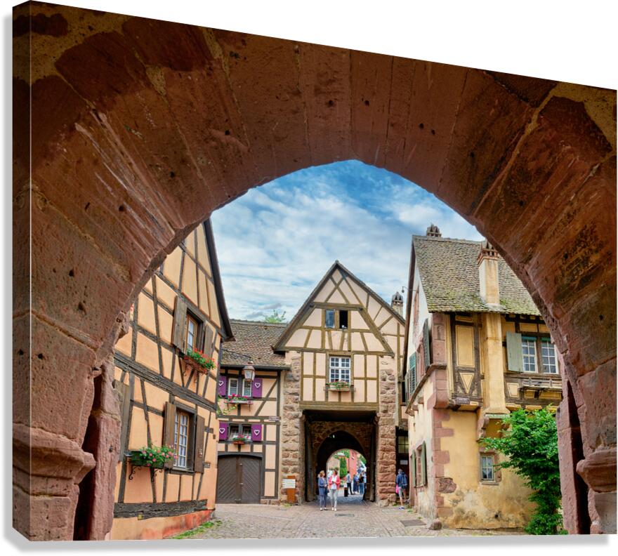 Visitors walk through an archway in Riquewihr