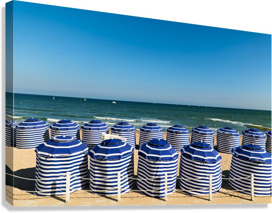Beach scene in Cabourg Normandy with striped umbrellas on sand