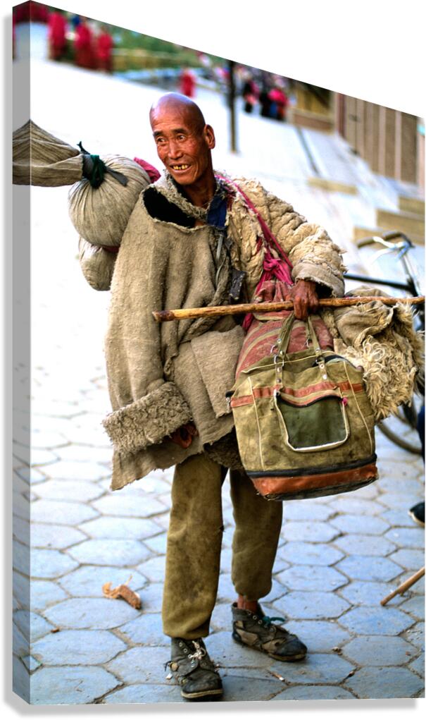 Smiling man carries bundles while walking on street in Tibet