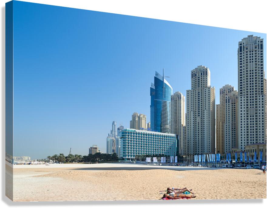 Sunbathers enjoy beach near city skyline in Dubai UAE