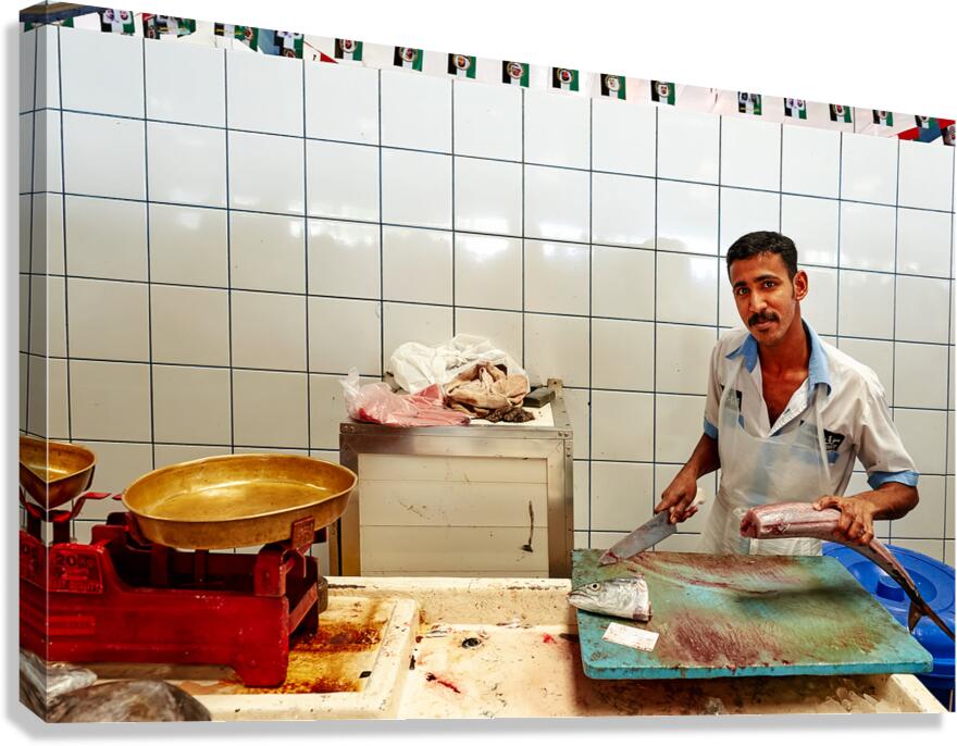 Man cuts fish at a market stall in Dubai during daylight hours