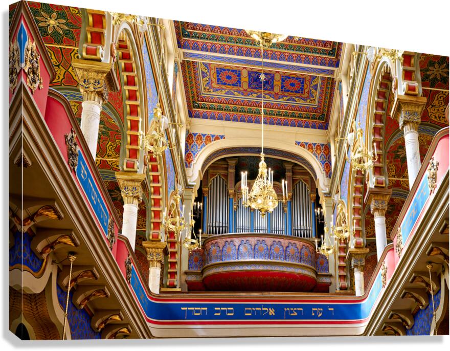 Ornate synagogue interior with organ and chandeliers.