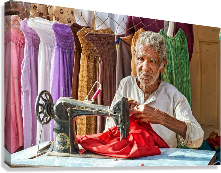 Elder man sewing red fabric in Jaisalmer Rajasthan India