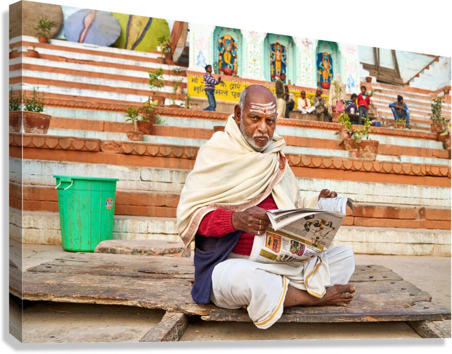 Man reads newspaper by river in Varanasi India