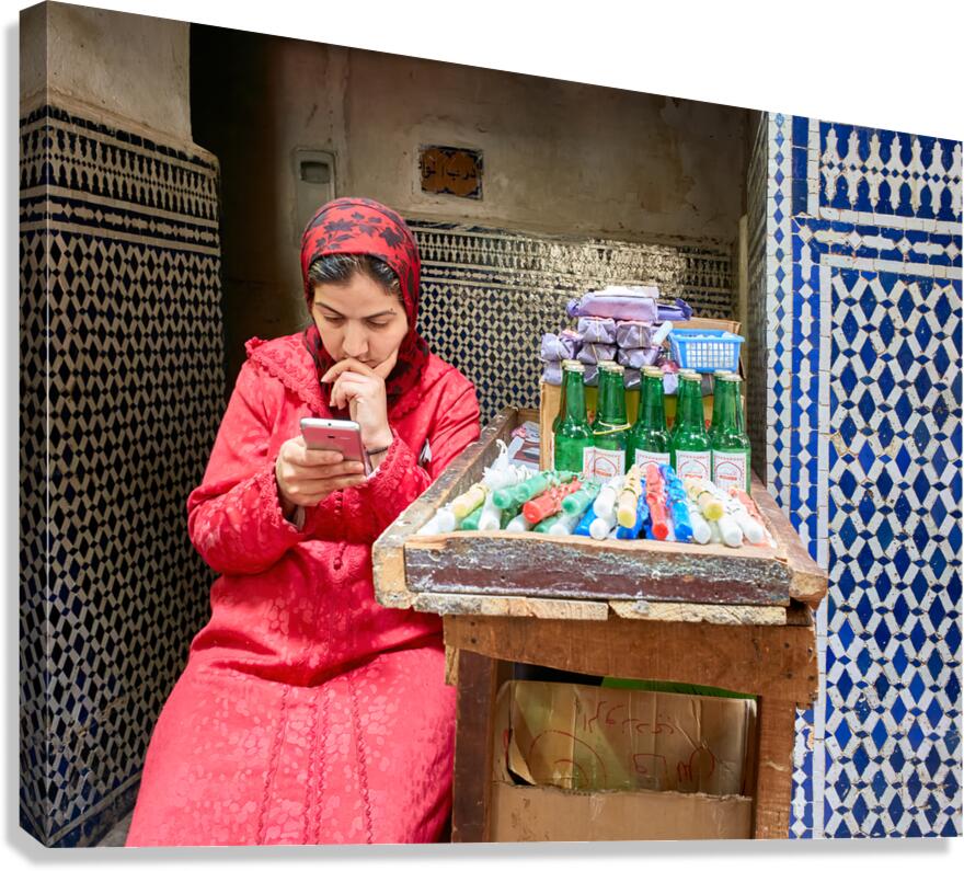 Woman using smartphone in Fez Medina while sitting by a stall