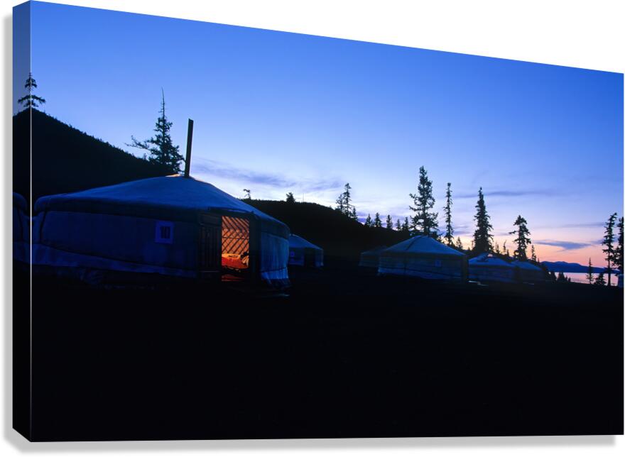 Yurts at sunset in Mongolia with pine trees and mountains in vie