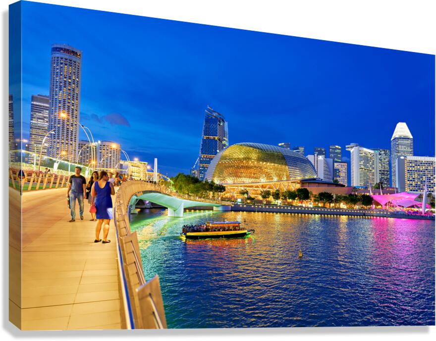 People walk by Marina Bay waterfront as city lights turn on at s