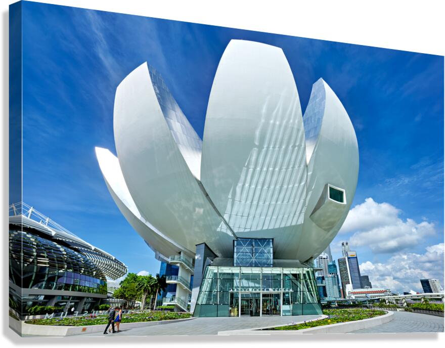 Visitors look at ArtScience Museum with city skyline on a clear 