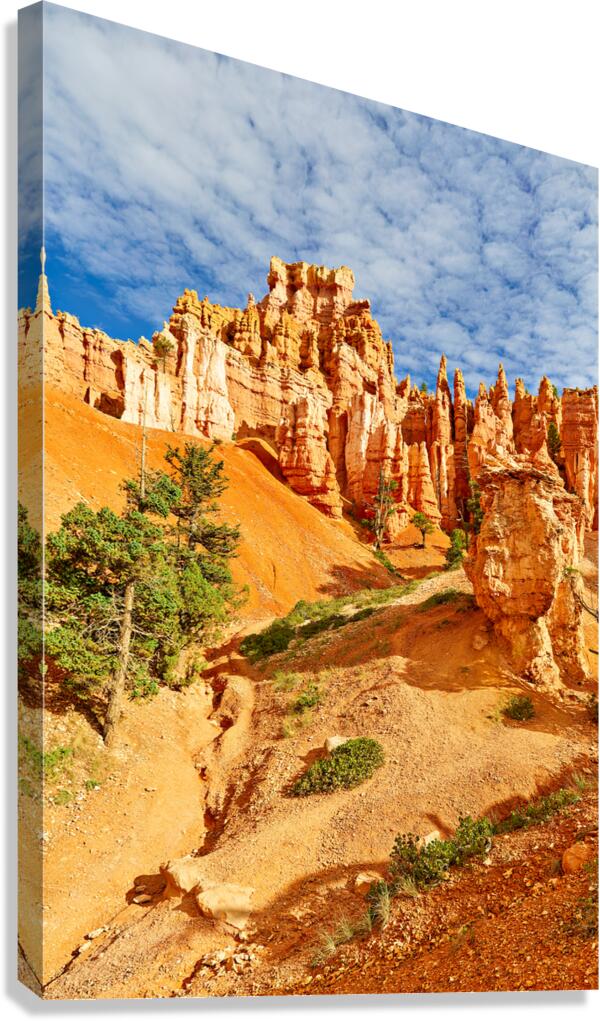 Visitors walk through Queens Garden in Bryce Canyon National Park. Tall rock formations and clouds fill the sky during daylight.