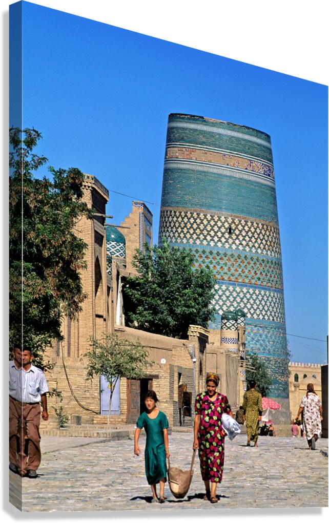 Women and children walk by the tall tower in Khiva Uzbekistan