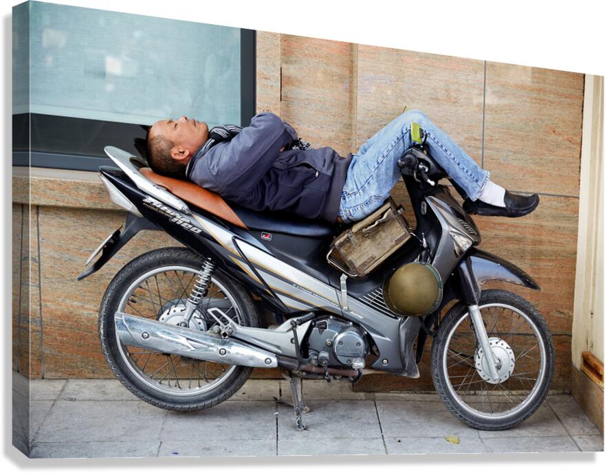 Man resting on motorcycle in Hanoi during the day