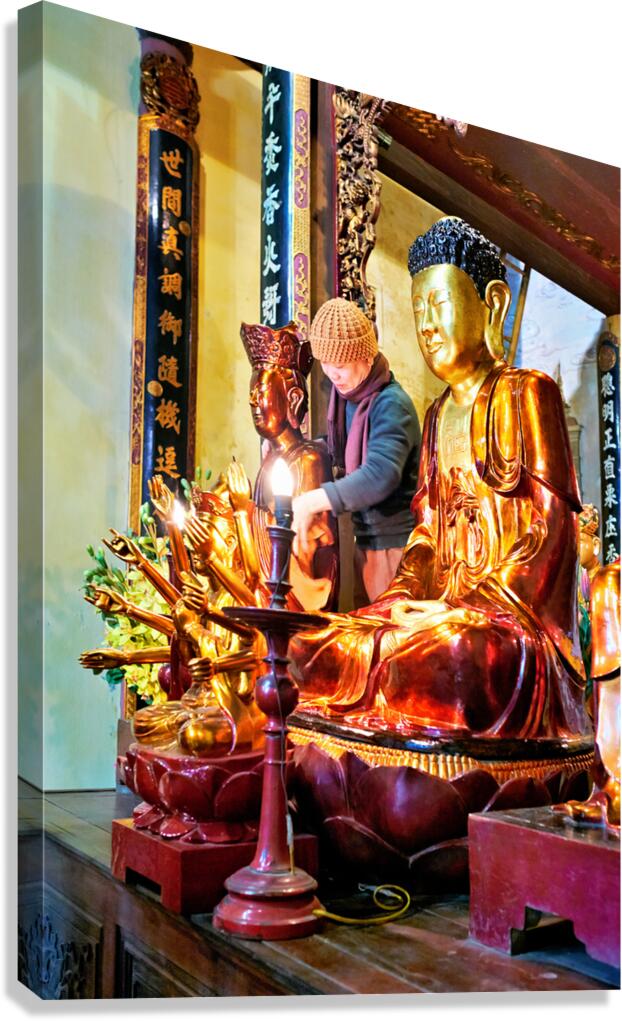 Buddhist monk praying near golden statues in Hanoi