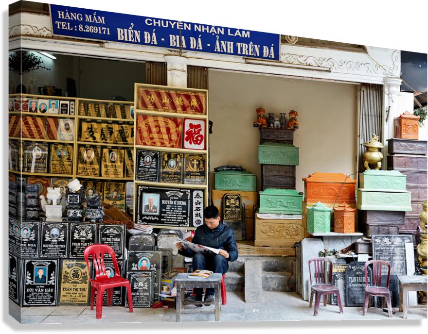 Craftsman works at a shop in Hanoi Vietnam while reading