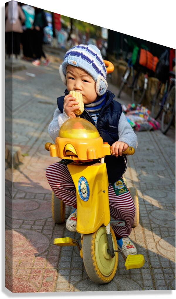 Child enjoys snack while riding tricycle in Hanoi streets