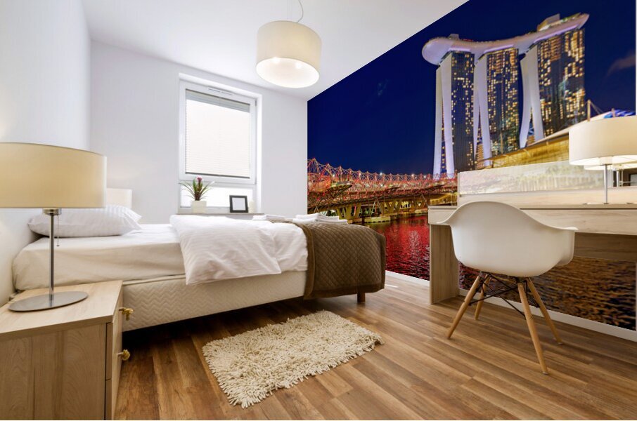 People walk across the Helix Bridge as the Marina Bay Sands Hotel shines at sunset. The sky turns orange and lights reflect in the water. Mural print