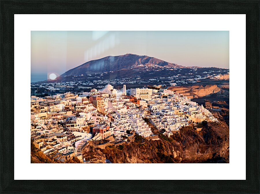 Santorini cliffside town at sunset with mountain backdrop. Picture Frame print