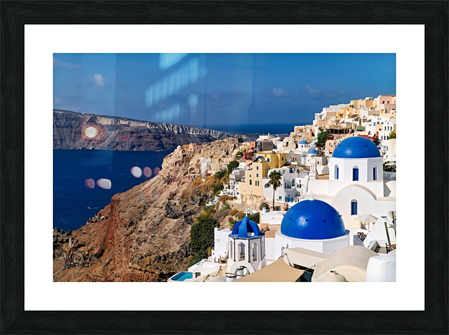 Santorinis iconic white buildings and blue domes overlooking th Picture Frame print