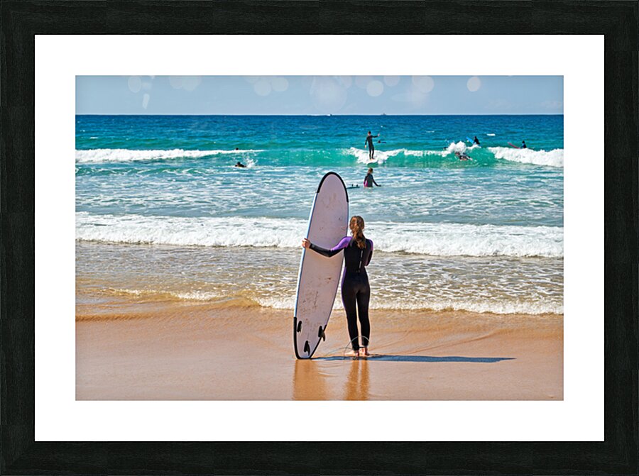 Surfer girl with surfboard on beach watching waves Picture Frame print