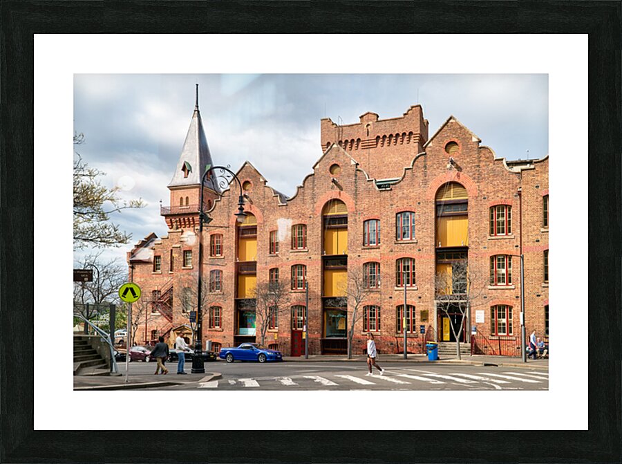 Historic brick building with a tower and people walking. Picture Frame print