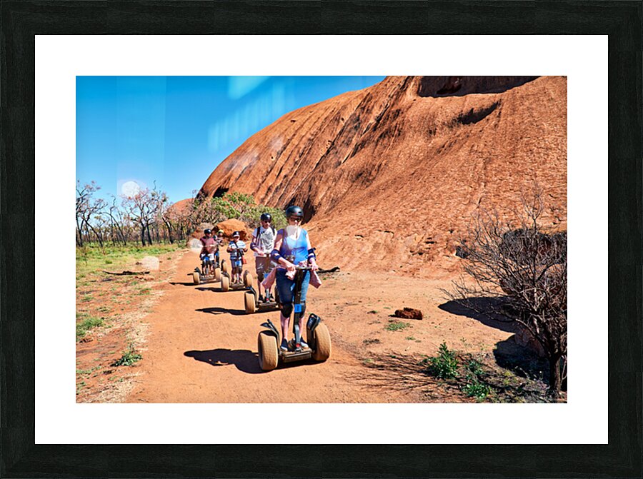 Tourists ride Segways near Uluru in Australia. Picture Frame print
