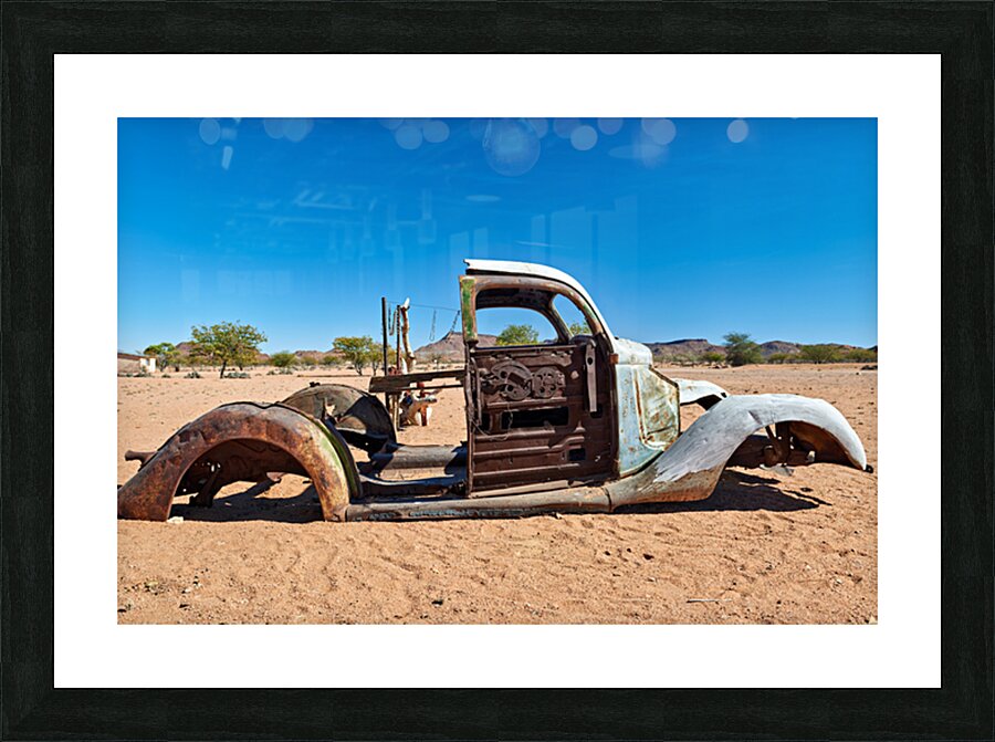 Classic car wreck rests in the Namib desert under a clear sky Picture Frame print