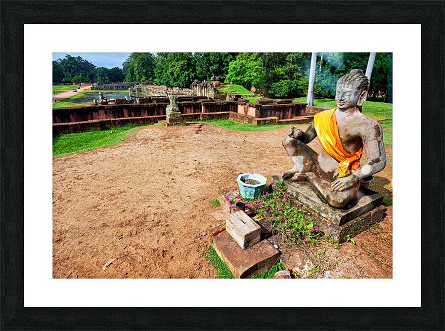 Ancient statue overlooks temple ruins amidst lush greenery. Picture Frame print