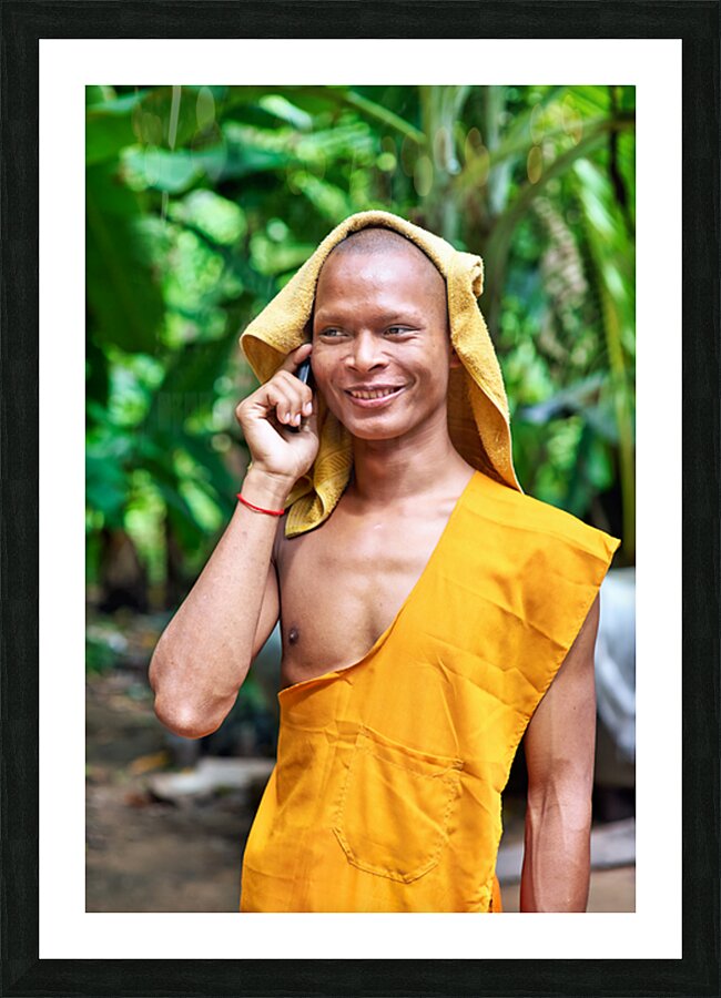 Smiling monk talks on phone with towel on head. Picture Frame print