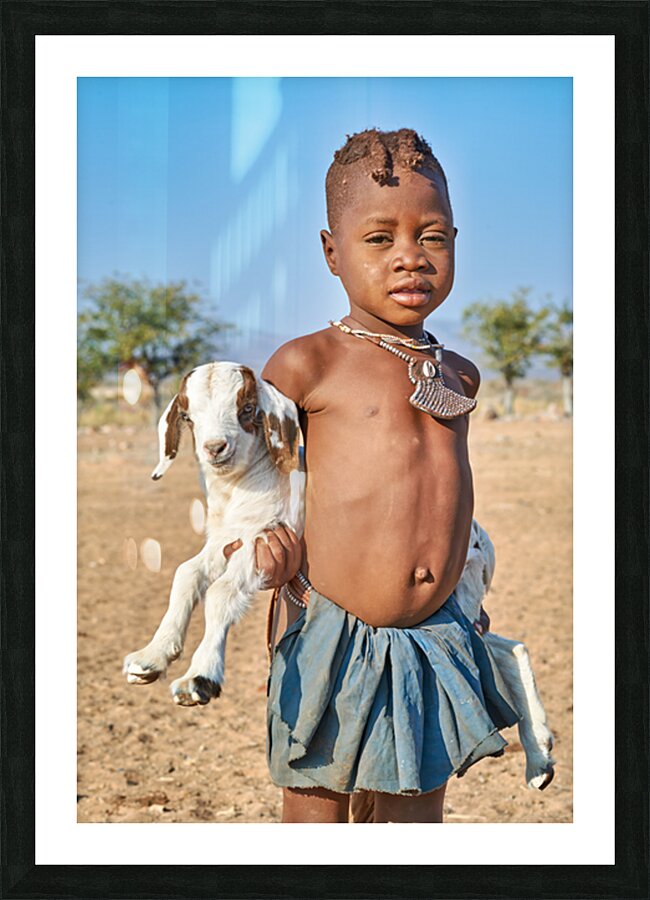 Himba child holding a goat in Kunene Region of Namibia Picture Frame print