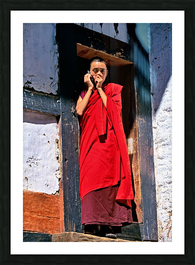 Monk in red robes on cell phone. Picture Frame print