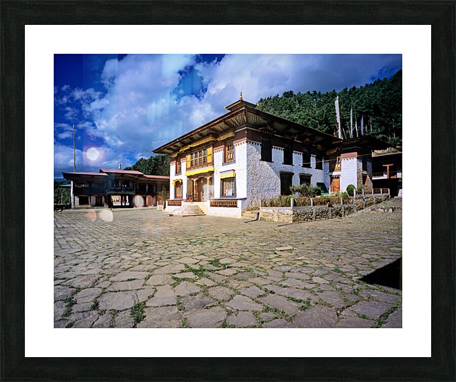 Traditional Bhutanese building with stone courtyard under a clou Picture Frame print