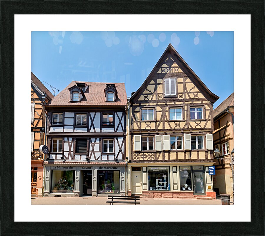 Visitors explore timber framed houses in Colmar Alsace on a sun Picture Frame print