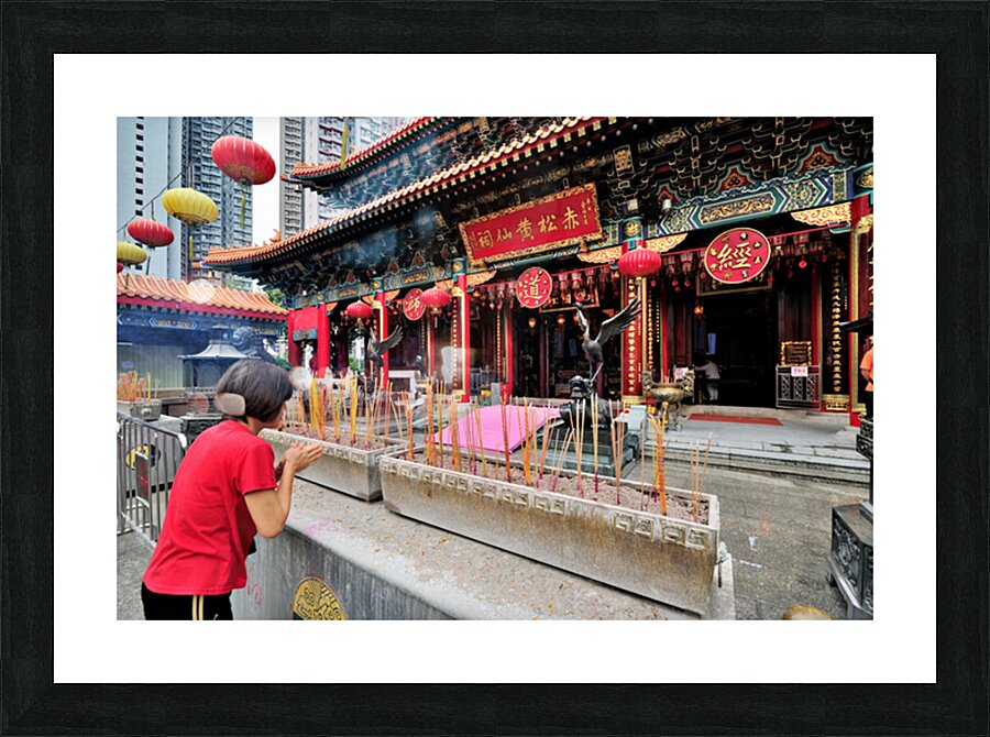 Woman prays with incense at colorful Chinese temple in Hong Kong Picture Frame print