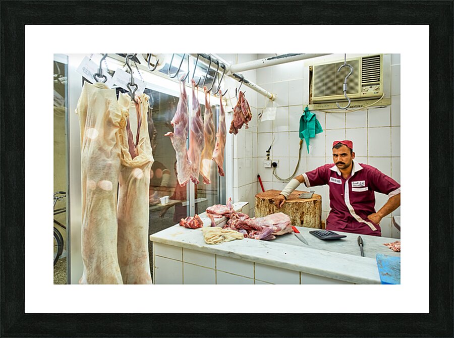 Butcher works in meat market in Dubai with hanging meat Picture Frame print