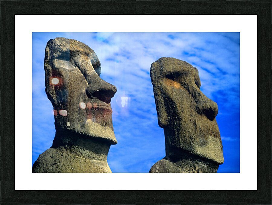 Two Moai statues against a blue sky. Picture Frame print