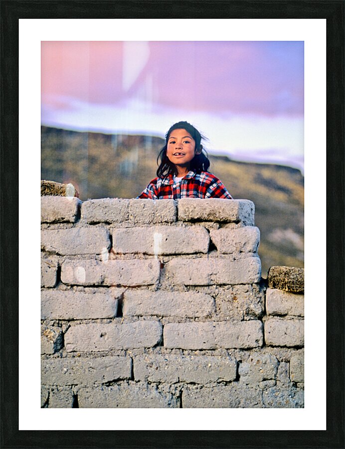 Young girl smiles over stone wall at sunset. Picture Frame print