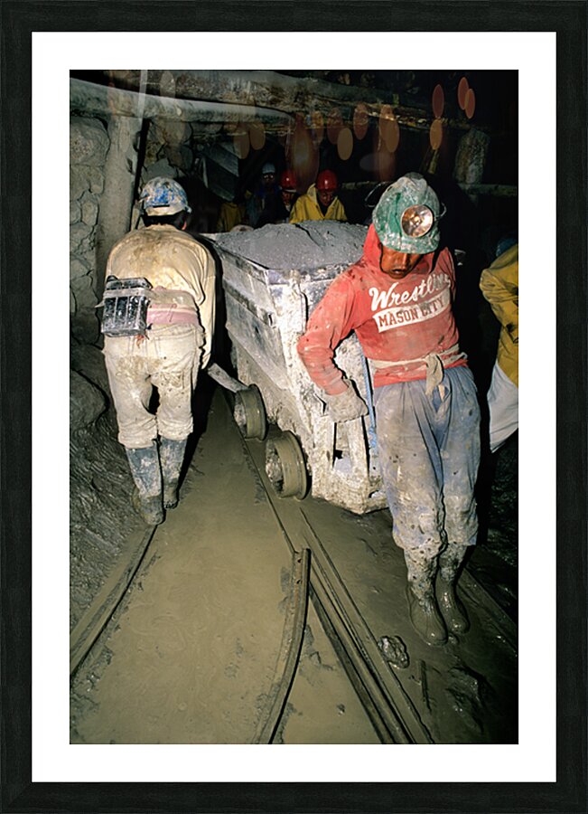 Miners pushing a loaded cart through a muddy underground mine. Picture Frame print
