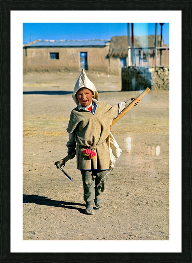 Indigenous boy with tools walks through a dusty village. Picture Frame print