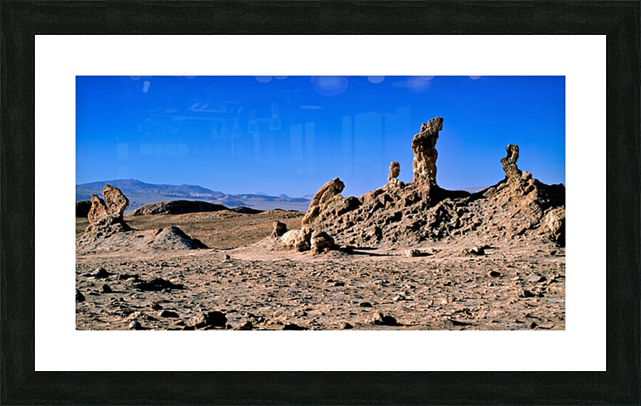 Arid desert with unusual rock pillars against a blue sky. Picture Frame print