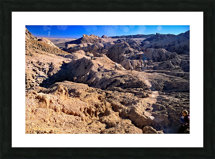 Hikers traverse a vast arid rocky desert landscape. Picture Frame print