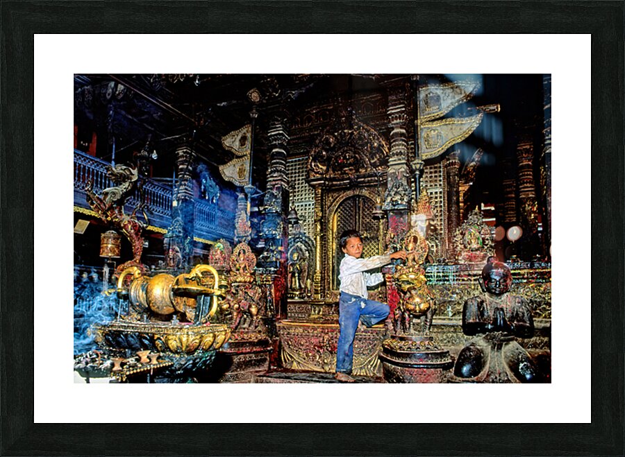 Boy interacts with religious artifacts in Kathmandu temple Picture Frame print
