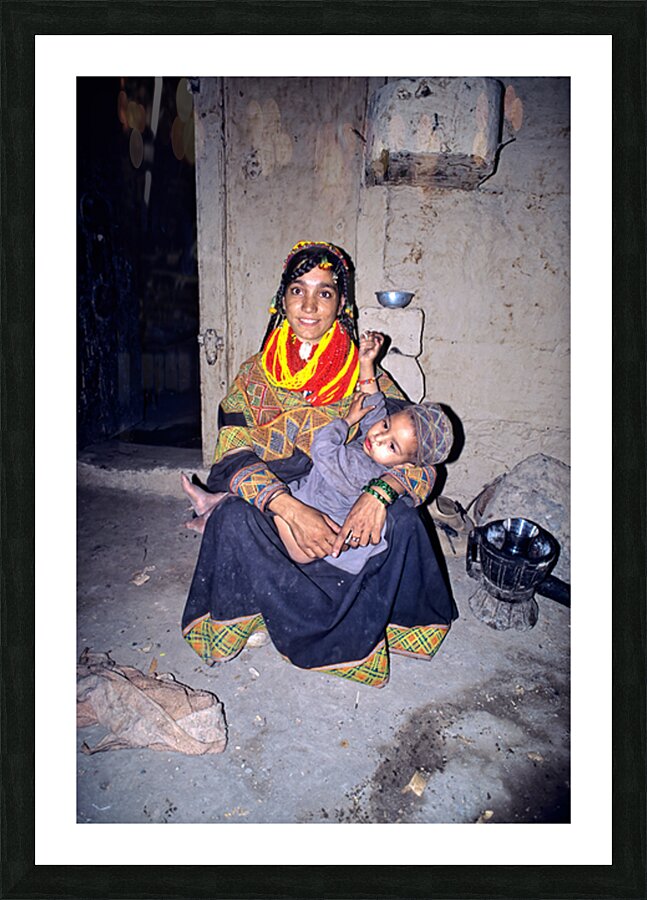 A woman holds her child in a Kalash village Picture Frame print