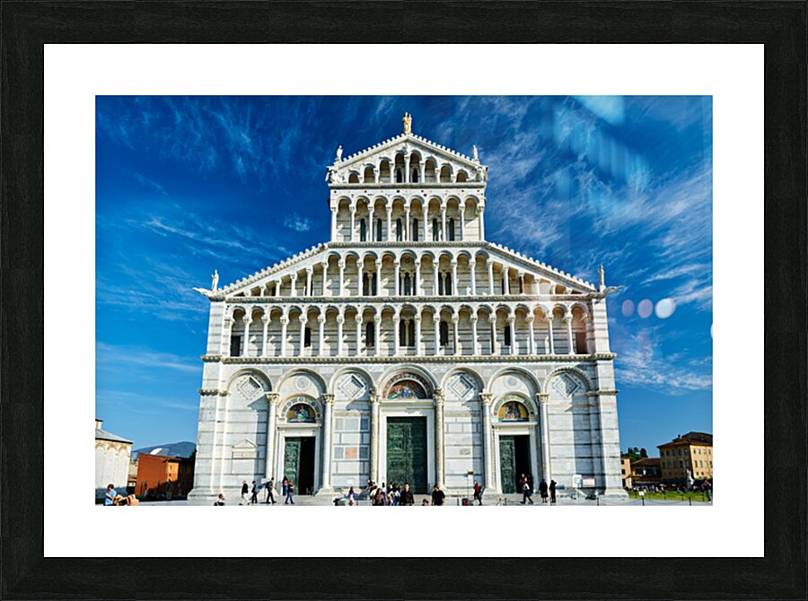 Visitors walk around Pisa Cathedral in Piazza dei Miracoli. The tall structure stands under a blue sky. People enjoy the lively atmosphere. Picture Frame print