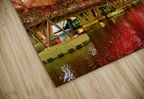 People walk across the Helix Bridge as the Marina Bay Sands Hotel shines at sunset. The sky turns orange and lights reflect in the water. Marco Brivio puzzle