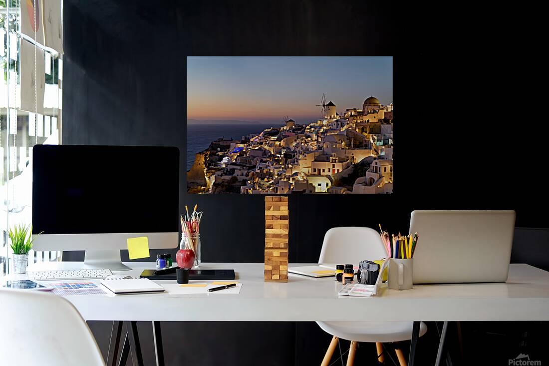 Santorinis Oia village glows at twilight by the sea. Reproduction