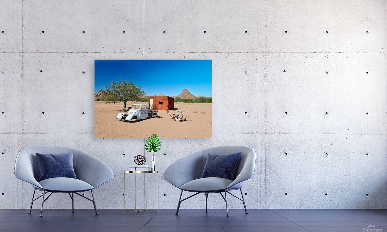 Classic car wreck in Namibias desert landscape near a structure Reproduction
