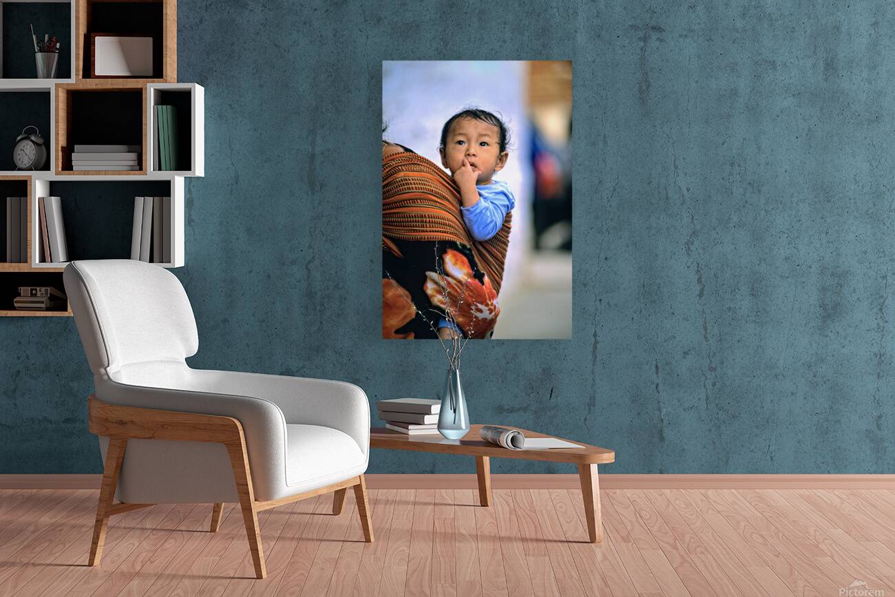 Curious child carried in a patterned fabric sling. Reproduction