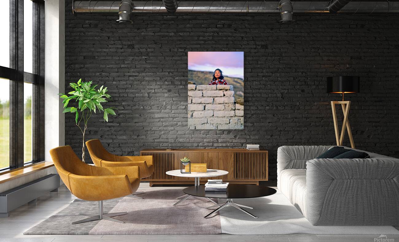 Young girl smiles over stone wall at sunset. Reproduction