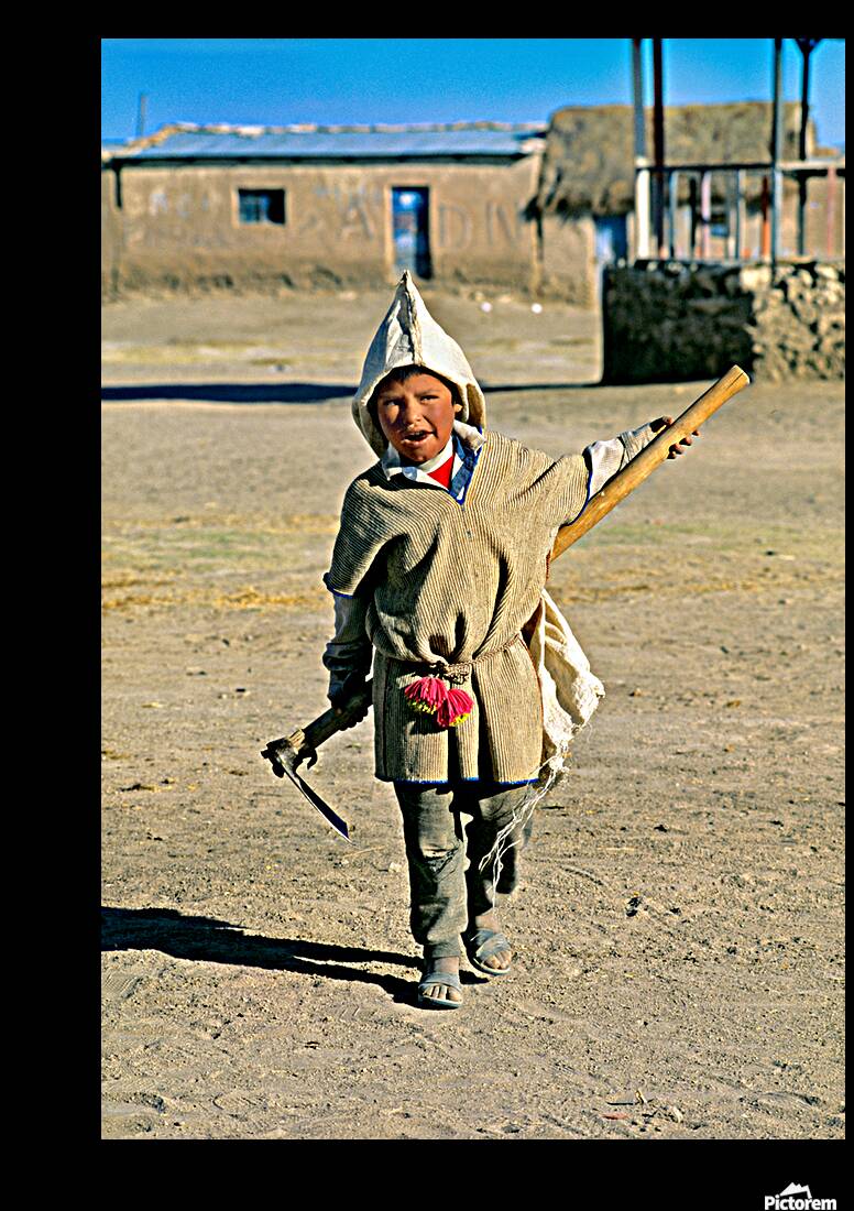 Indigenous boy with tools walks through a dusty village. Reproduction