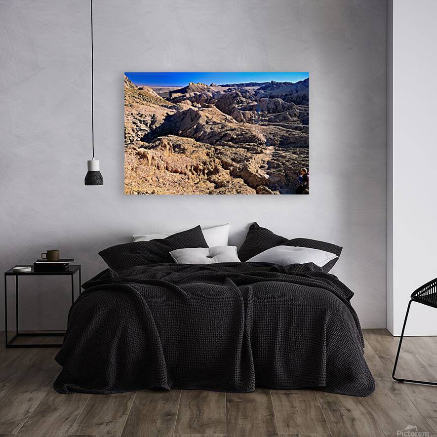 Hikers traverse a vast arid rocky desert landscape. Reproduction