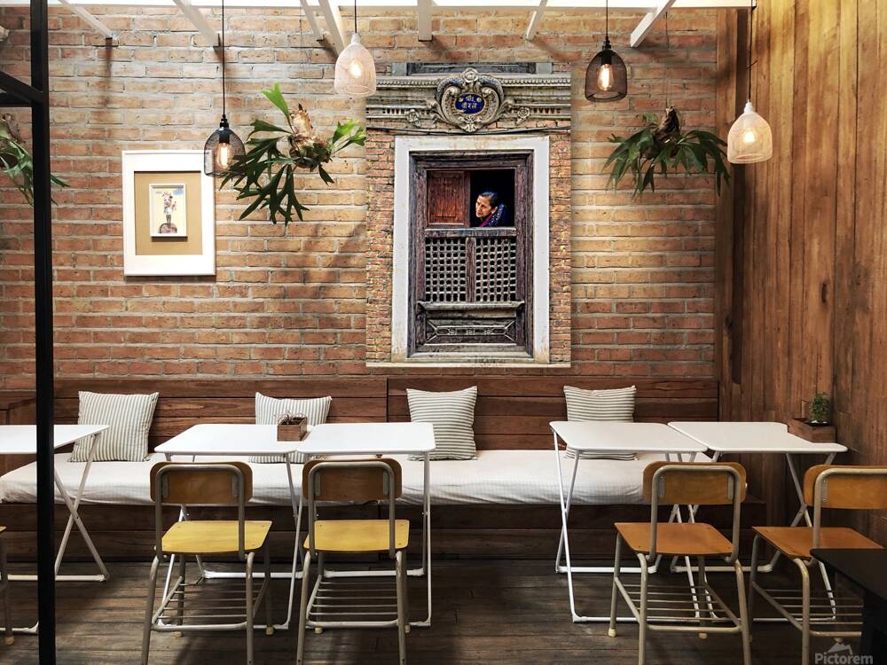 Woman in Kathmandu looks out from window in old building Reproduction